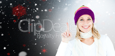 Composite image of joyful woman with a colorful hat pointing upw