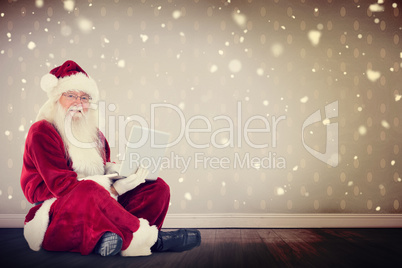 Composite image of santa sits and uses a laptop