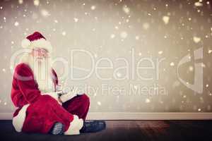 Composite image of santa sits and uses a laptop