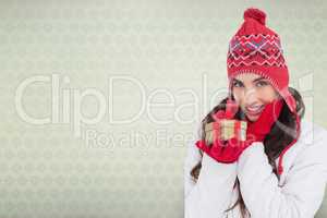 Composite image of surprised brunette in winter clothes holding