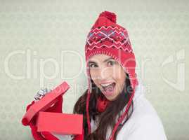 Composite image of excited brunette opening a christmas gift