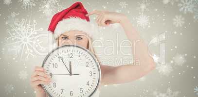 Composite image of festive blonde holding a clock