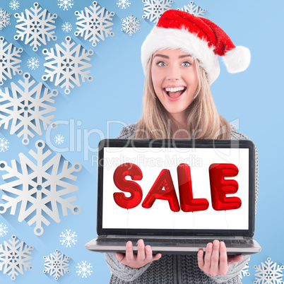 Composite image of festive blonde holding a laptop