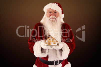 Composite image of santa holds a tiny house in his hands