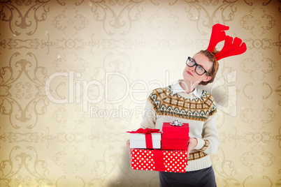 Composite image of thoughtful geeky hipster holding presents