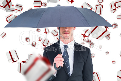 Composite image of unsmiling businessman sheltering under umbrel