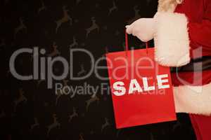 Composite image of santa claus holding sale bag
