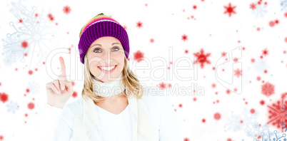 Composite image of joyful woman with a colorful hat pointing upw