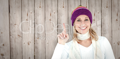 Composite image of joyful woman with a colorful hat pointing upw