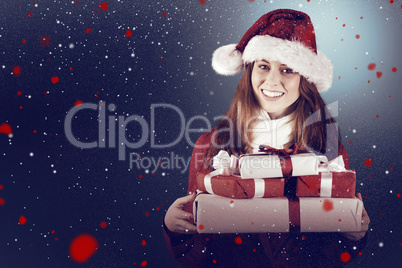 Composite image of festive redhead holding pile of gifts