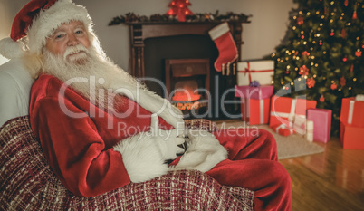 Smiling santa sitting and holding his belly