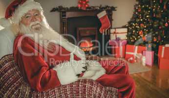 Smiling santa sitting and holding his belly