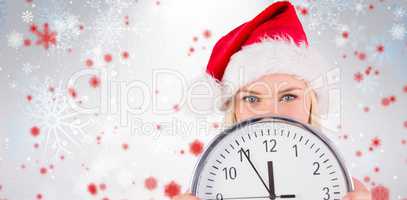 Composite image of festive blonde holding a clock