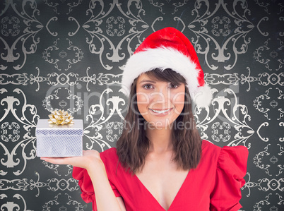 Composite image of festive brunette holding a gift