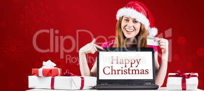 Composite image of festive redhead shopping online with laptop