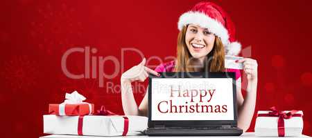 Composite image of festive redhead shopping online with laptop