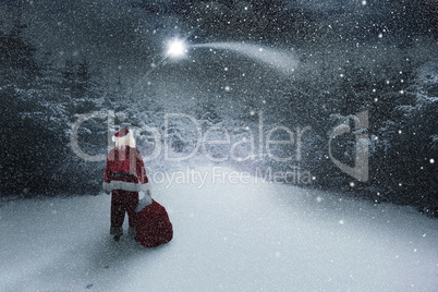 Composite image of santa carrying sack of gifts