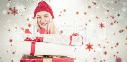 Composite image of festive blonde holding pile of gifts