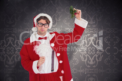 Composite image of geeky hipster in santa costume holding mistle