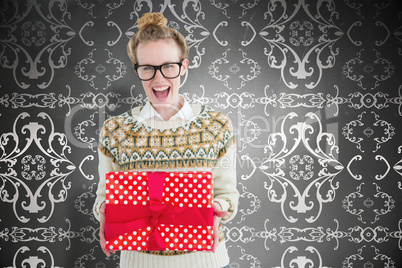 Composite image of excited geeky hipster holding present
