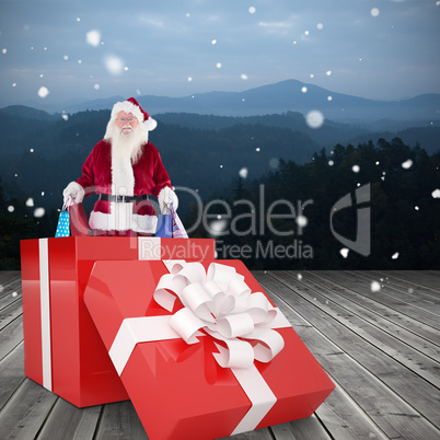 Composite image of santa standing in large gift