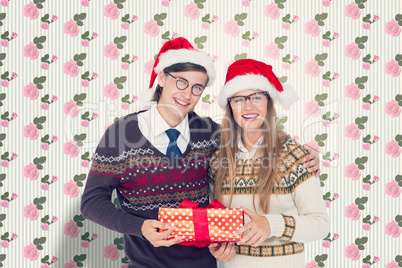 Composite image of geeky hipster couple holding present