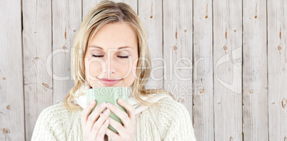 Composite image of happy woman enjoying a hot coffee standing