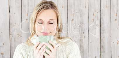 Composite image of happy woman enjoying a hot coffee standing