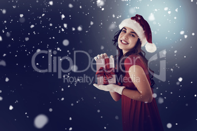 Composite image of festive brunette showing gift
