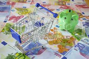 Einkaufswagen auf Eurogeldscheinen mit Sparschwein