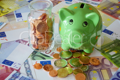Sparschwein und Glas mit Euromünzen auf Geldscheinen