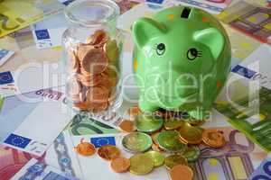 Sparschwein und Glas mit Euromünzen auf Geldscheinen