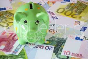 Grünes Sparschwein und Euro Geldscheine zum Thema Finanzen