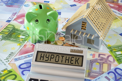 Das Wort Hypothek auf Display von Taschenrechner und Sparschwein