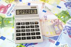 Das Wort Sparen auf Display von Taschenrechner auf Eurogeldschei