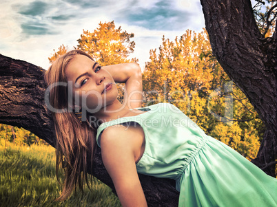 Young sensual blonde girl lying on a tree branch