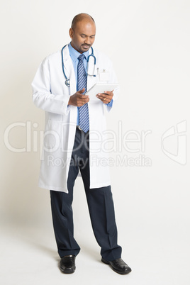 Mature Indian doctor full length using tablet pc