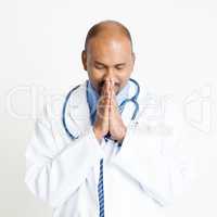 Mature Indian doctor praying