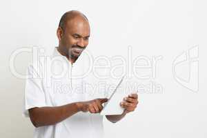Mature casual business Indian man using tablet pc