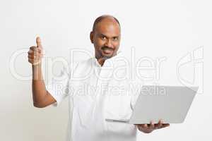 Mature Indian man using laptop and thumb up