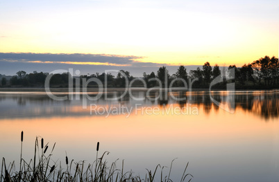 The morning landscape with sunrise over water in the fog