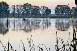 A fisherman in a boat sailing in the morning mist