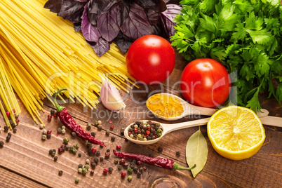 Raw pasta, vegetables, basil and spices on the wood table