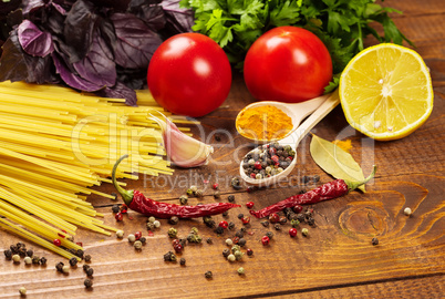 Raw pasta, vegetables, basil and spices on the wood table