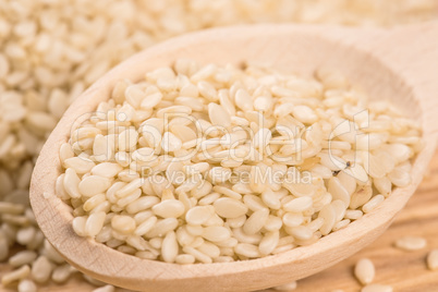 Organic natural sesame seeds in the wooden spoon on wood table