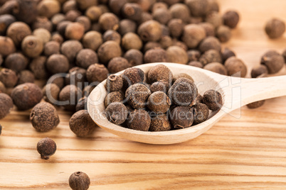 allspice in a wooden spoon on the wood table