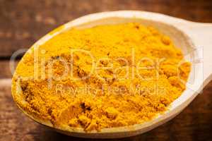 Close up of measuring spoon in pile of organic turmeric (curcuma) powder