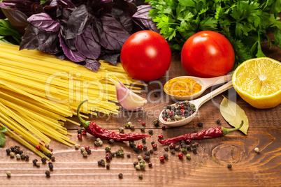 Raw pasta, vegetables, basil and spices on the wood table