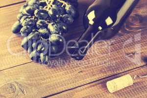 Bottle of white wine, grape and corks on wooden table