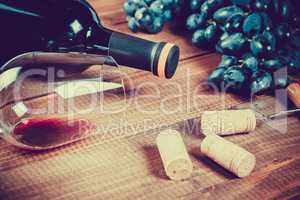 Bottle of white wine, grape and corks on wooden table